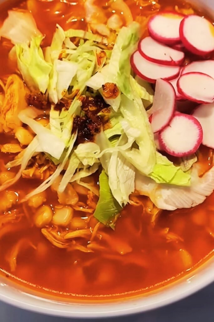 Bowl of reheated pozole with fresh garnishes